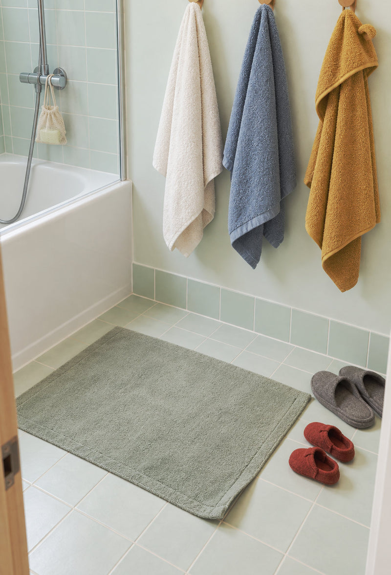 Salle de bain familiale avec tapis de bain et serviettes