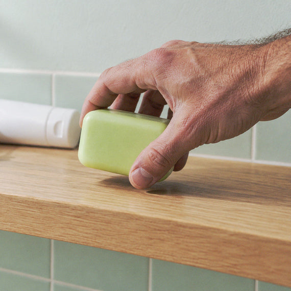 Main qui prend le savon, le tube de crème mis de côté