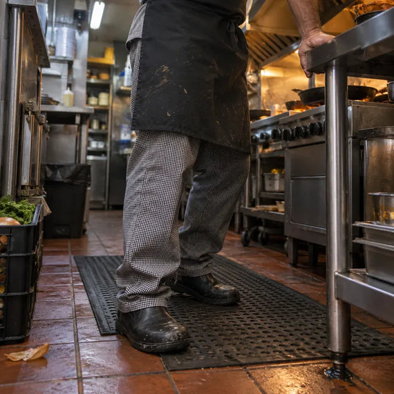 Cuisinier debout sur un tapis antifatigue dans une cuisine de restaurant