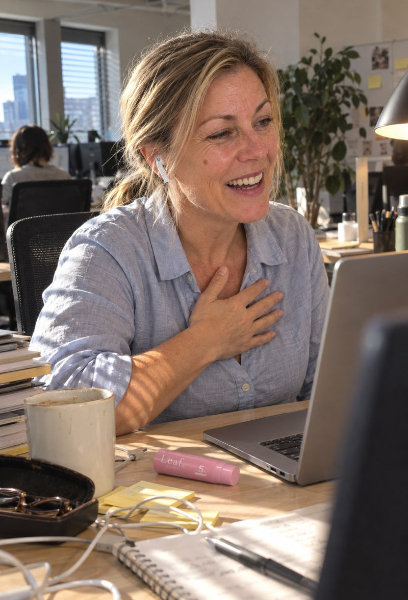 Femme qui rit en appel vidéo à son bureau, le stick près du clavier