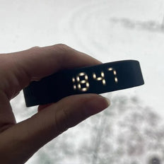 Bracelet WAKE qui affiche 8:47 devant une fenêtre enneigée
